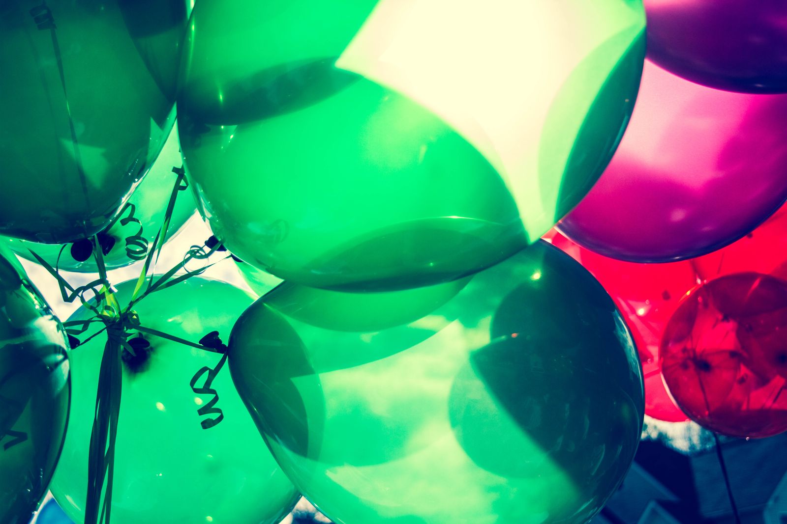 Bunch of green pink and red party balloons outdoors