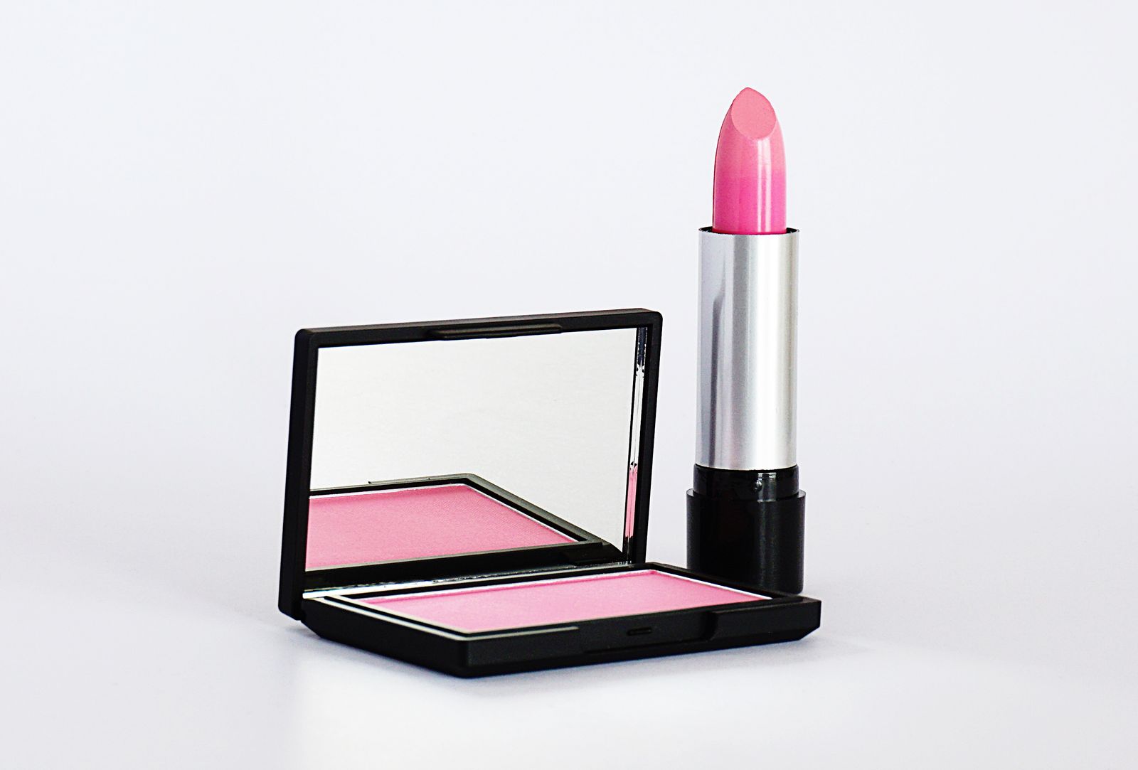 Pink lipstick and open blush compact product shot