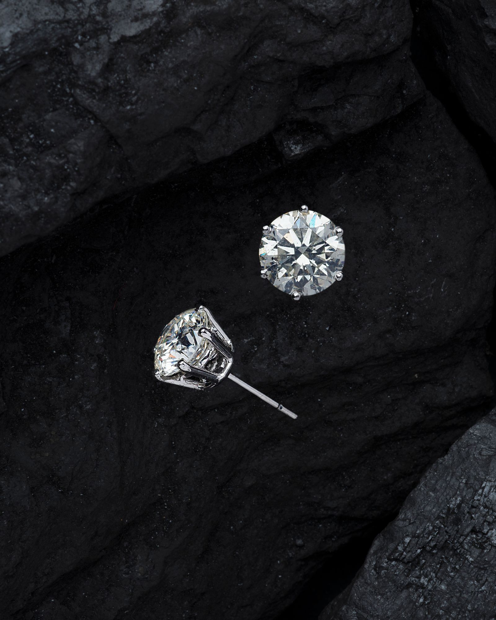 Pair of clear stud earrings displayed on a dark stone surface
