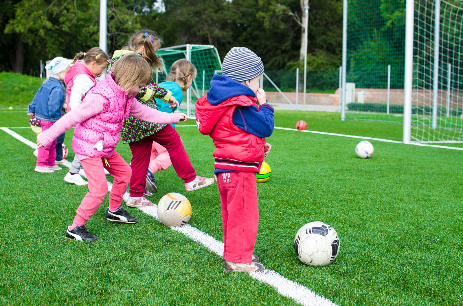 Children playing with soccer balls on an outdoor sports field