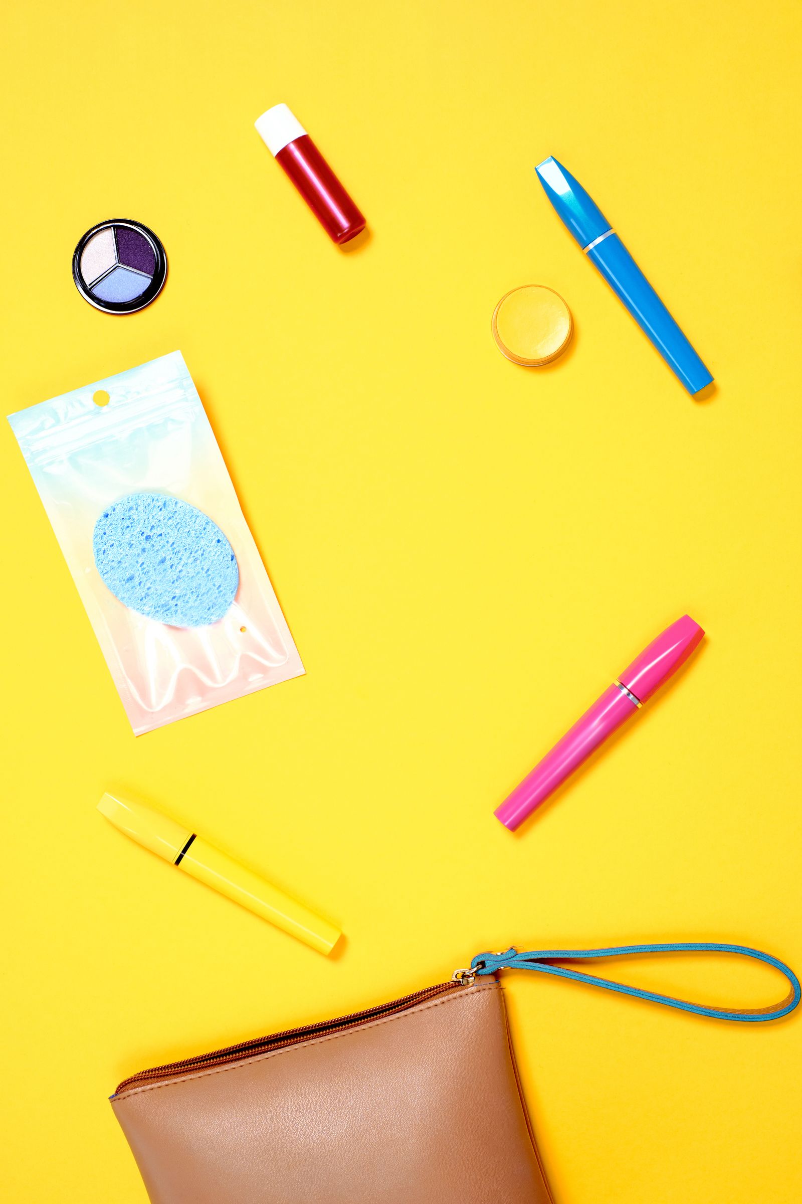 Cosmetic pouch with makeup tools flat lay on yellow