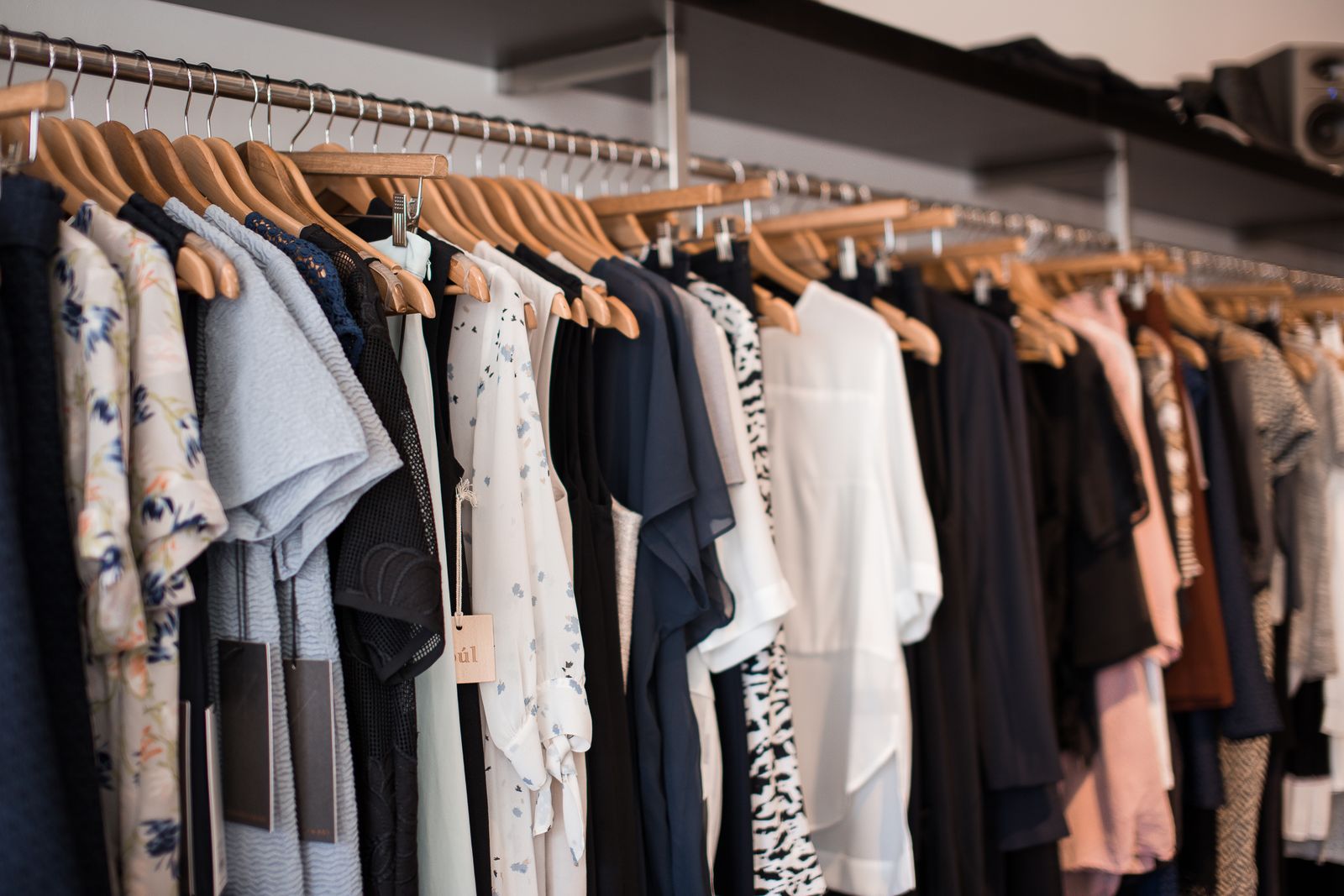 Mixed apparel pieces hanging on wooden hangers in a boutique rack