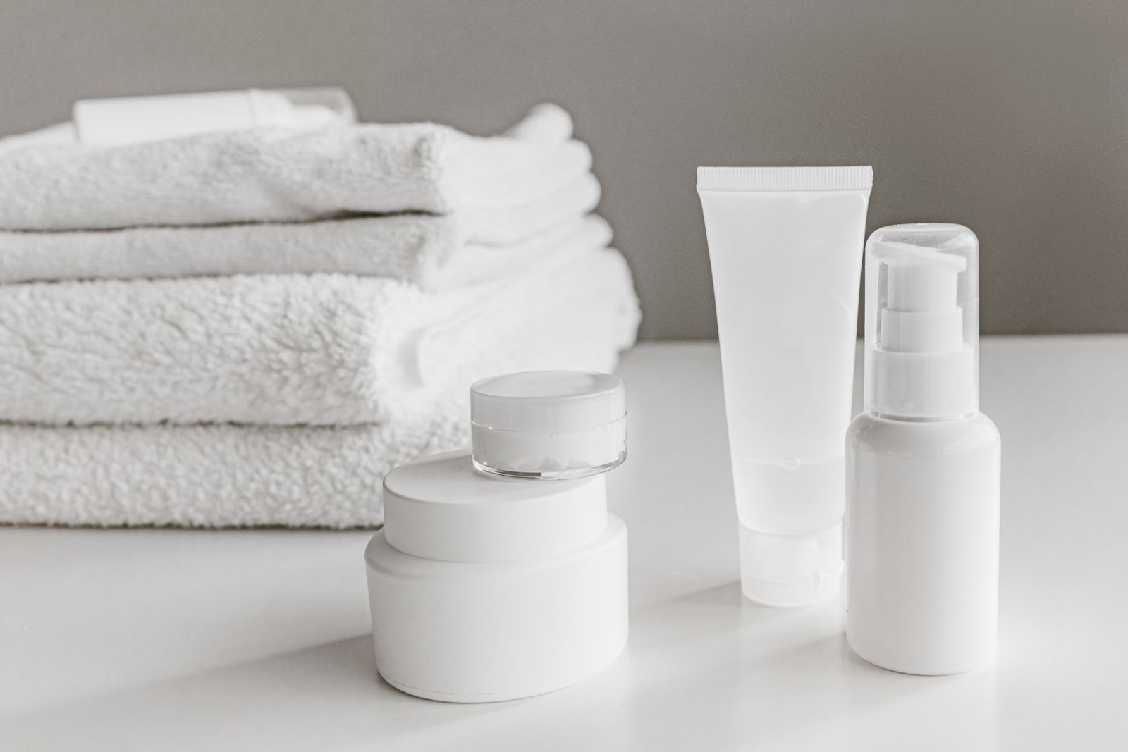 White unbranded skincare bottles arranged with towels