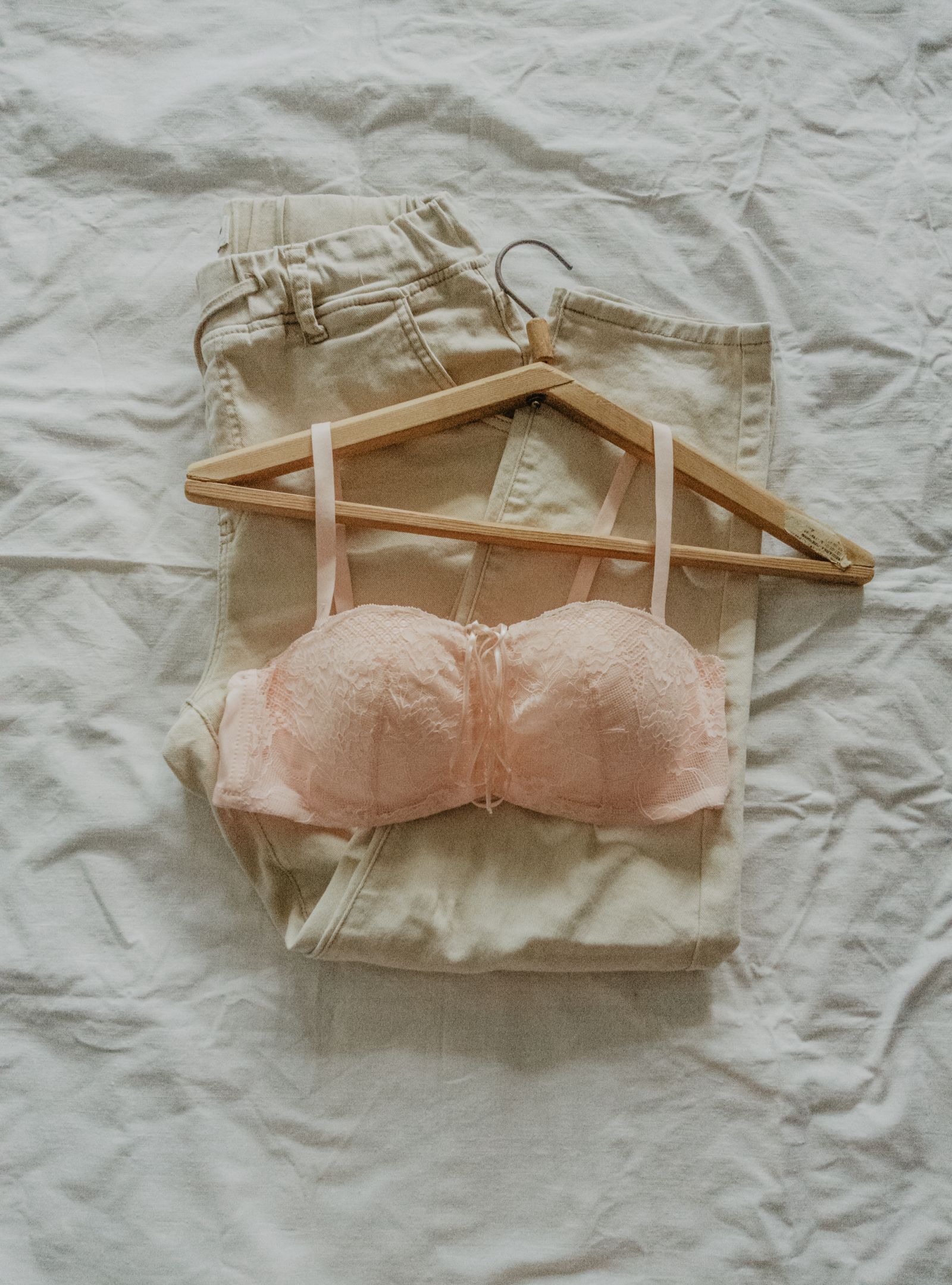 Pink lace undergarment and trousers arranged as a product flat lay